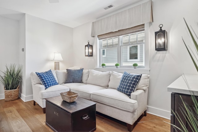 living room featuring visible vents, baseboards, and light wood finished floors