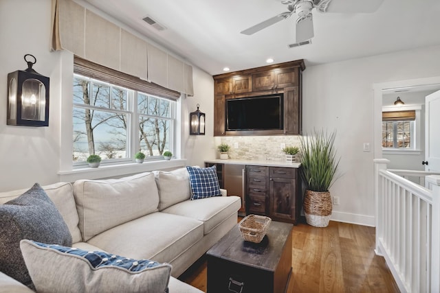 living room with recessed lighting, visible vents, light wood-type flooring, and baseboards