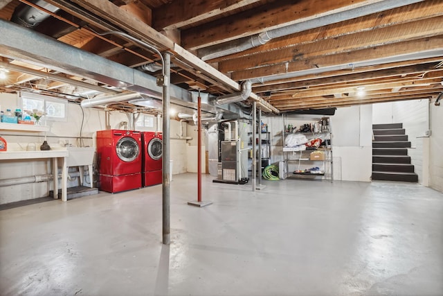 basement featuring a sink, heating unit, washing machine and dryer, and stairs