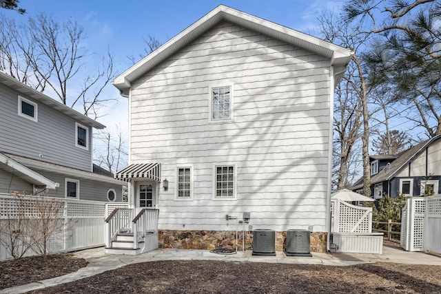 back of property with central AC unit and fence