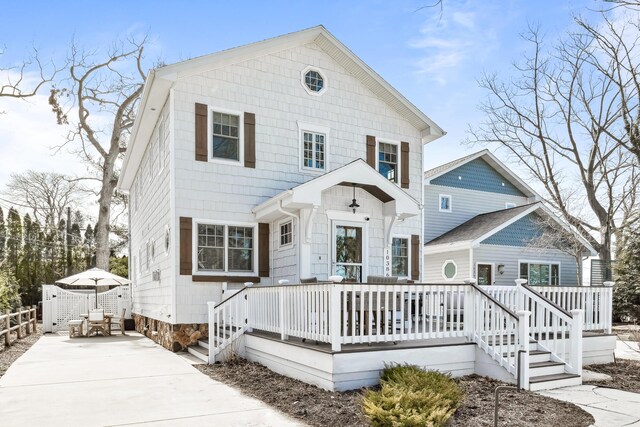 view of front of house with a deck, fence, and driveway