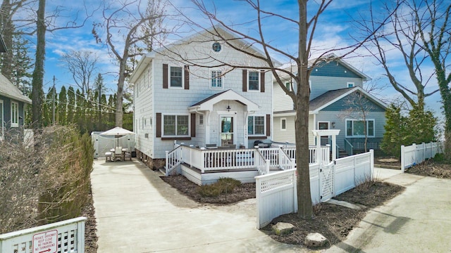 view of front of home with a fenced front yard, a wooden deck, and driveway