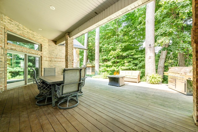 wooden terrace with a grill and outdoor dining area