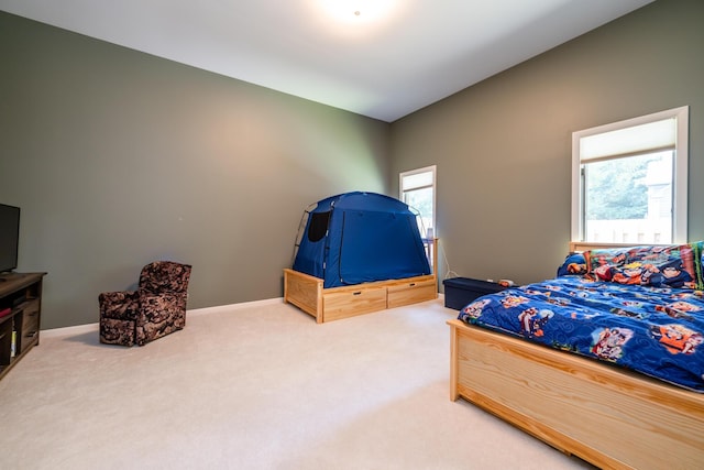 bedroom with multiple windows, light colored carpet, and baseboards