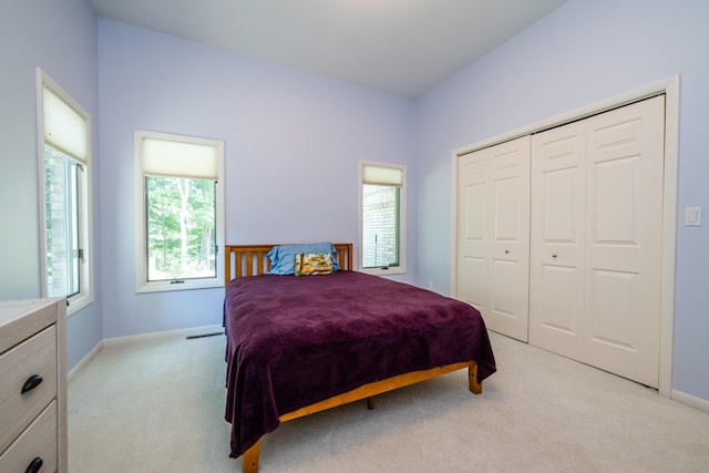 bedroom featuring light carpet, a closet, and baseboards