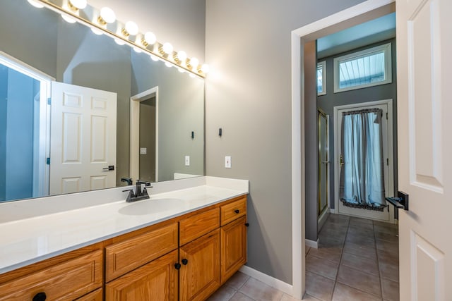 bathroom with tile patterned flooring, vanity, a stall shower, and baseboards