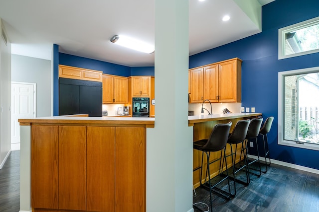 kitchen with baseboards, light countertops, a peninsula, fridge, and dark wood-style flooring