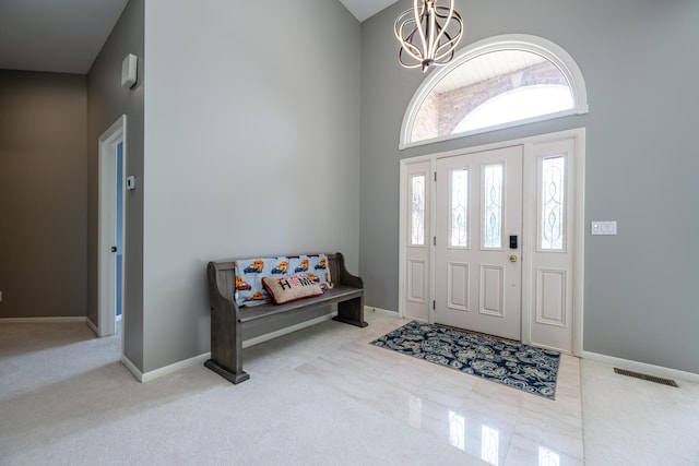 foyer entrance featuring visible vents, a notable chandelier, carpet floors, baseboards, and a towering ceiling