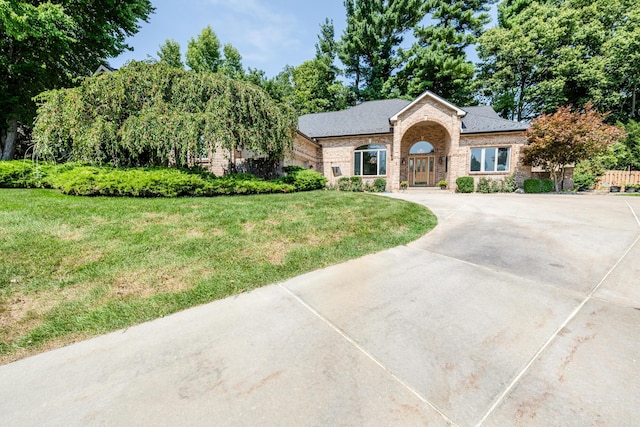 view of front of home with brick siding, concrete driveway, and a front lawn