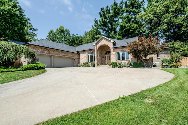 single story home with a front lawn, brick siding, a garage, and driveway