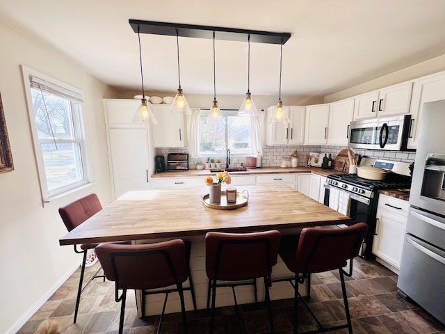 kitchen with a sink, tasteful backsplash, appliances with stainless steel finishes, and white cabinetry