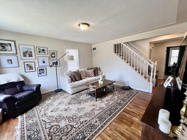 living area with stairs, wood finished floors, and baseboards