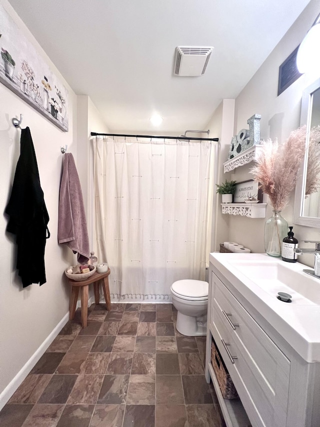 bathroom featuring visible vents, baseboards, toilet, stone finish floor, and vanity