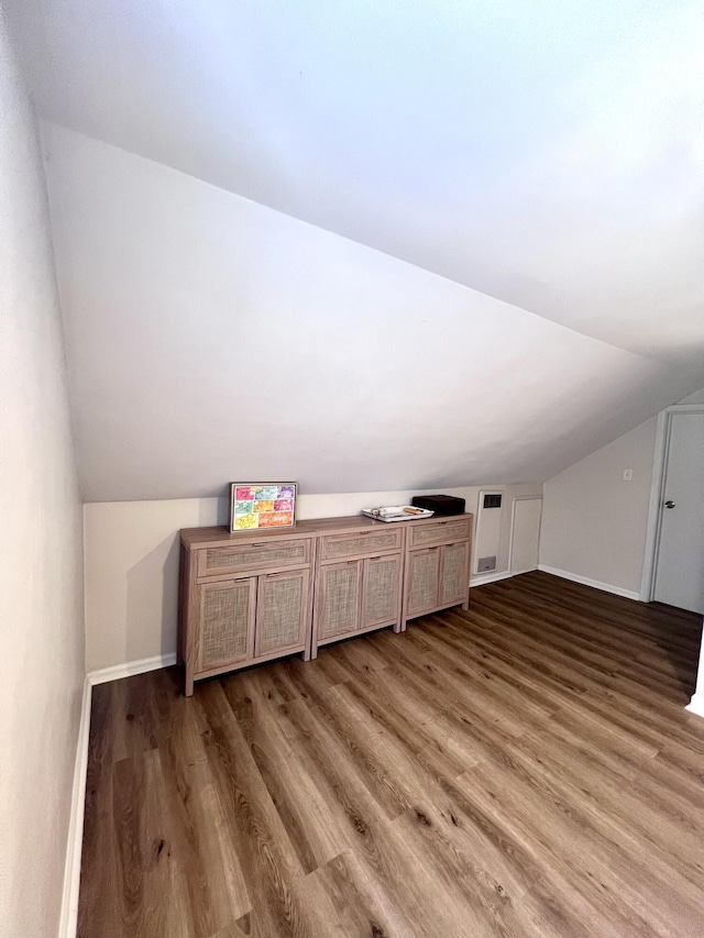 additional living space with vaulted ceiling, baseboards, and wood finished floors