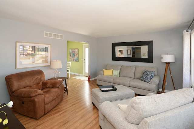 living room with baseboards, visible vents, and light wood finished floors