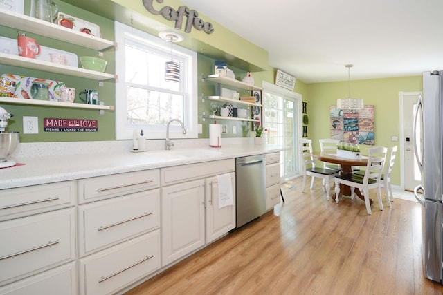 kitchen with light wood-type flooring, open shelves, decorative light fixtures, stainless steel appliances, and white cabinets