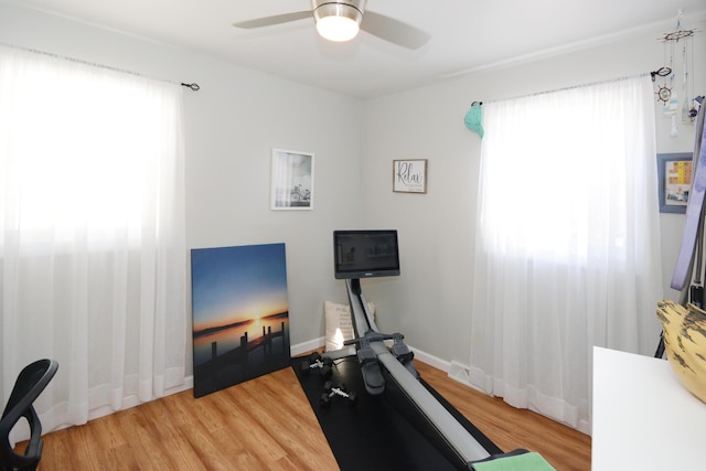 exercise room with baseboards, wood finished floors, and a ceiling fan