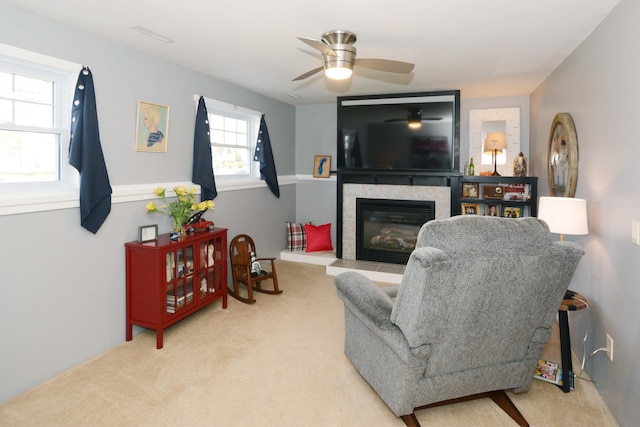 carpeted living area with ceiling fan and a tile fireplace