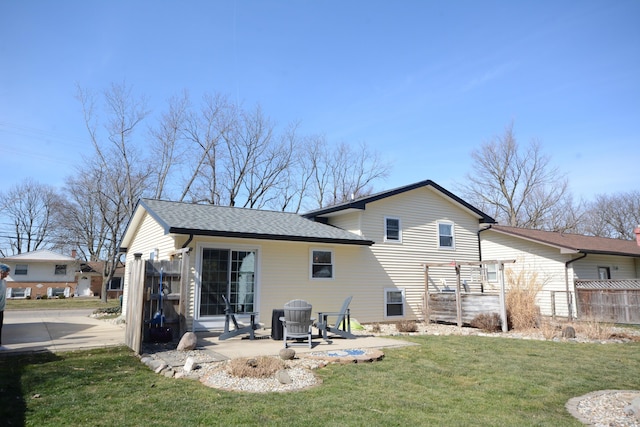 rear view of property featuring a patio area, a shingled roof, a yard, and fence