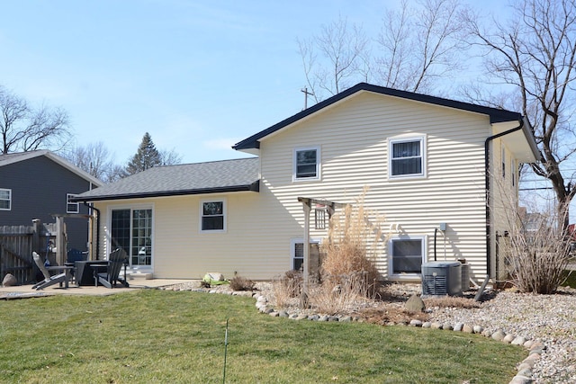 back of property with fence, central air condition unit, roof with shingles, a yard, and a patio