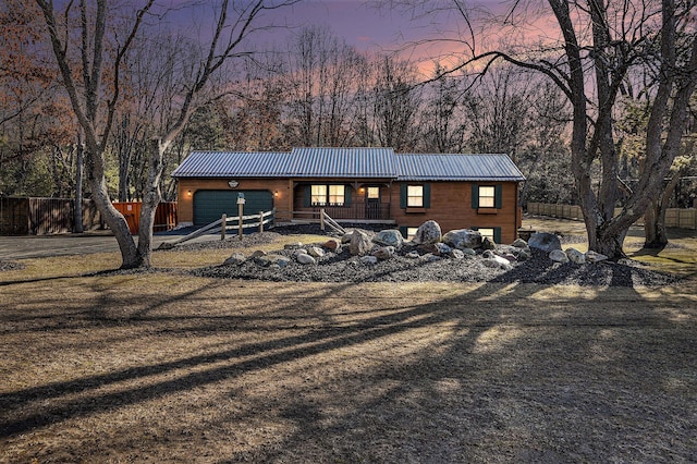 view of front of home with an attached garage, fence, and metal roof