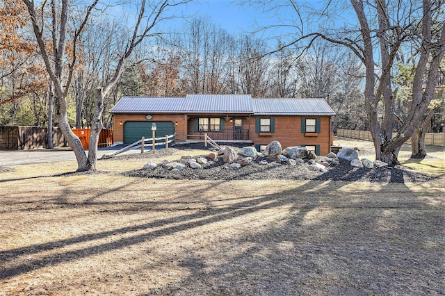 view of front of house with covered porch, metal roof, a garage, and fence