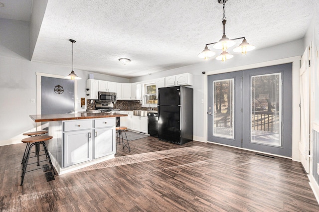 kitchen featuring butcher block countertops, a kitchen bar, dark wood-style floors, white cabinets, and black appliances