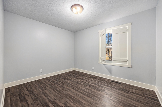 empty room with visible vents, a textured ceiling, baseboards, and dark wood-style flooring