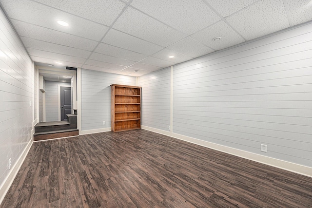 unfurnished room with a paneled ceiling, baseboards, and wood finished floors