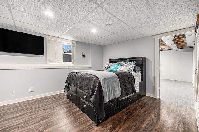 bedroom featuring wood finished floors, baseboards, and a paneled ceiling