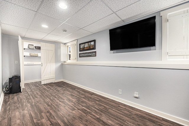 finished below grade area with a paneled ceiling, baseboards, and wood finished floors