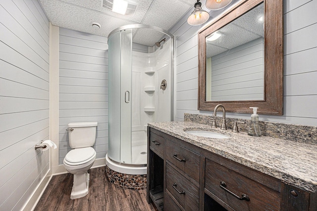 bathroom with visible vents, toilet, a stall shower, wood finished floors, and vanity