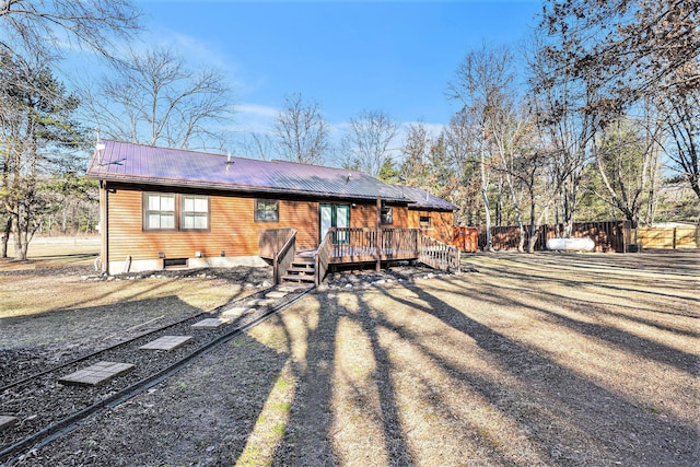 back of house featuring a wooden deck, metal roof, dirt driveway, and fence