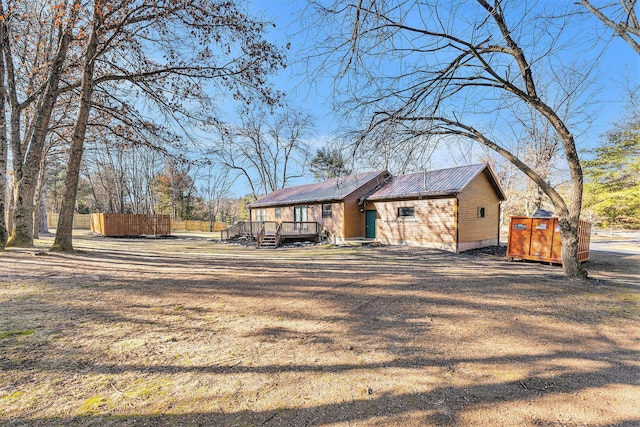 exterior space with a deck, driveway, and metal roof