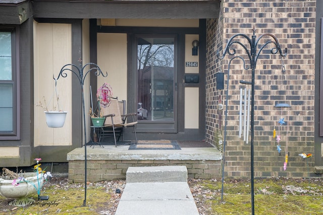 doorway to property with brick siding and covered porch