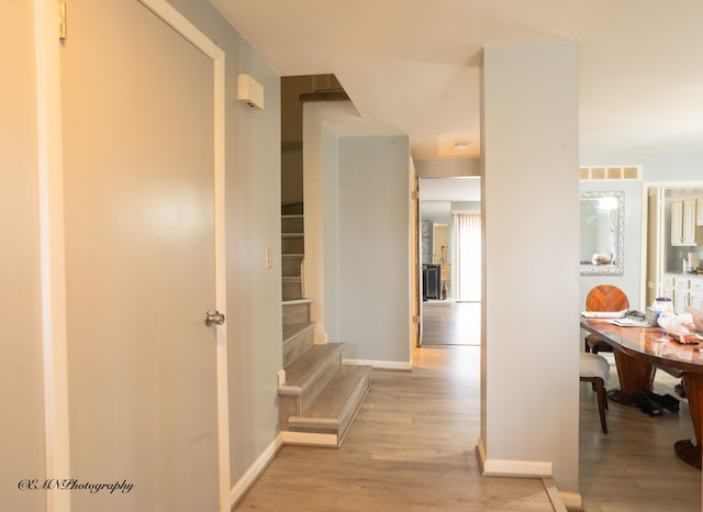 hallway featuring stairs, baseboards, and wood finished floors