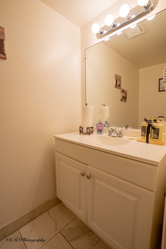 bathroom with marble finish floor, vanity, and baseboards