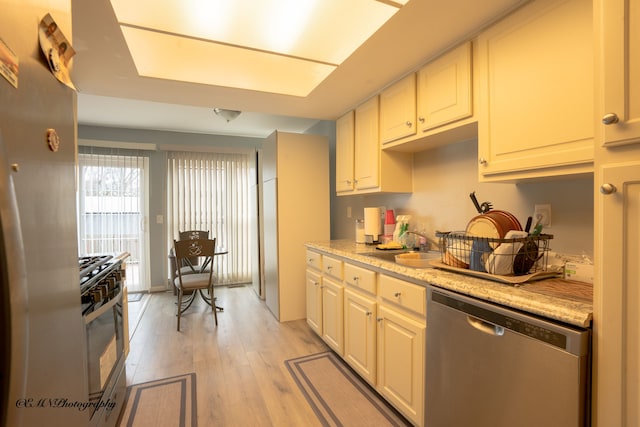 kitchen with light wood finished floors, appliances with stainless steel finishes, and a sink