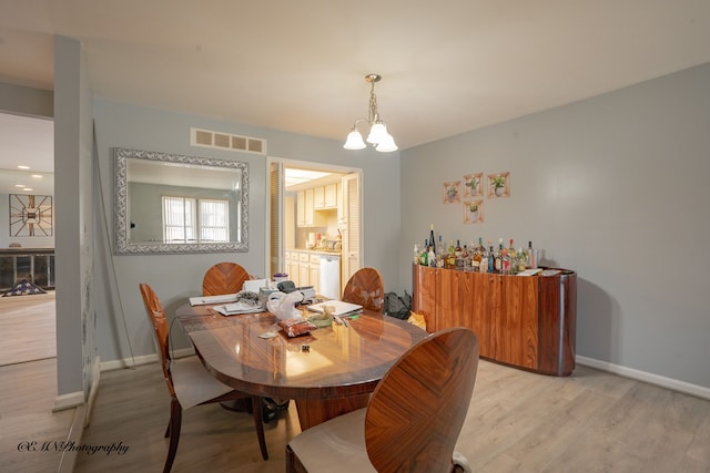 dining room featuring visible vents, baseboards, light wood-style flooring, and a chandelier