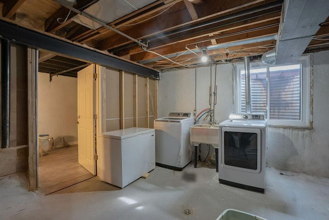 basement featuring refrigerator, separate washer and dryer, and a sink