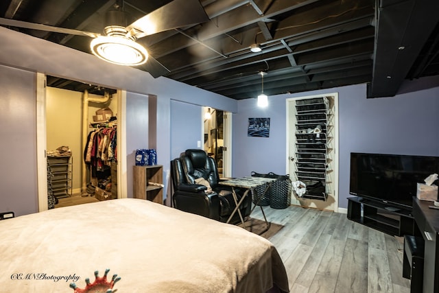 bedroom with a closet, wood finished floors, and a spacious closet