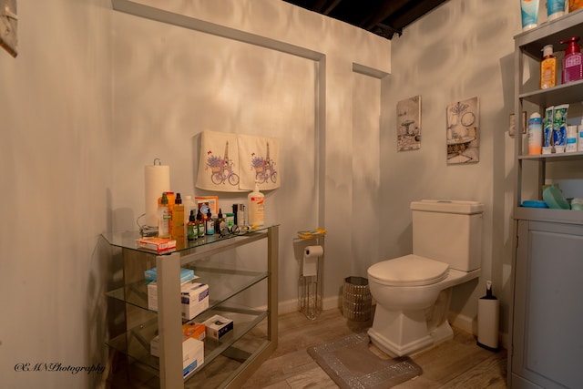 bathroom with toilet, wood finished floors, and baseboards