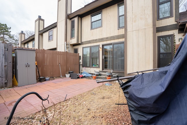 back of property featuring entry steps, a chimney, a patio, and fence