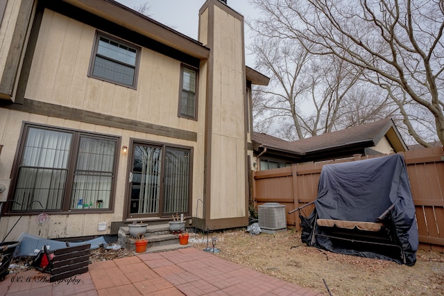 back of house featuring central air condition unit, fence, a chimney, and entry steps