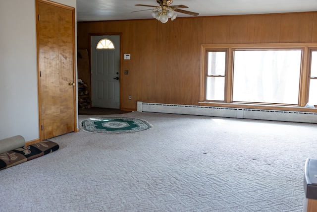 carpeted entryway with a baseboard heating unit, a ceiling fan, and wood walls