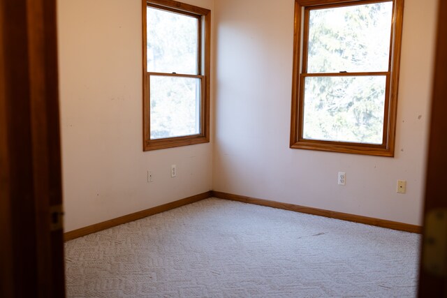 spare room with light carpet and baseboards