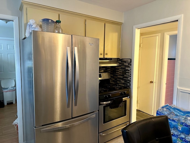 kitchen featuring decorative backsplash, under cabinet range hood, wood finished floors, and appliances with stainless steel finishes