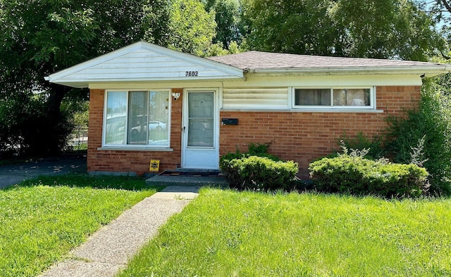 bungalow-style house with brick siding and a front yard