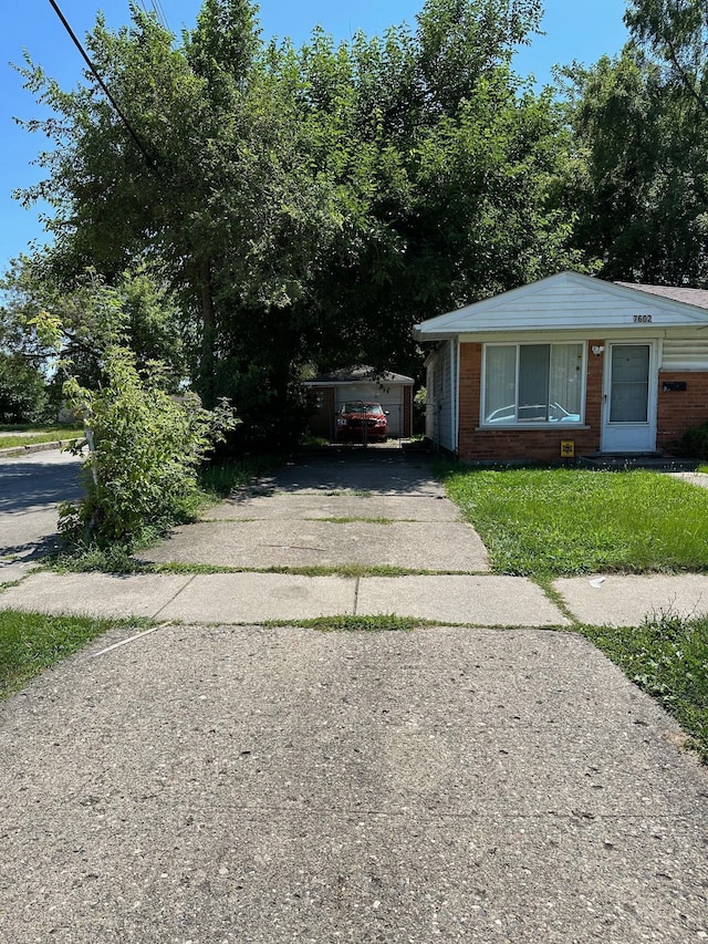 bungalow-style home featuring an outdoor structure, a front yard, brick siding, and driveway