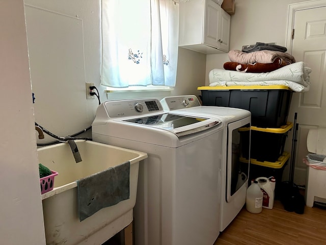 washroom featuring cabinet space, wood finished floors, washing machine and dryer, and a sink